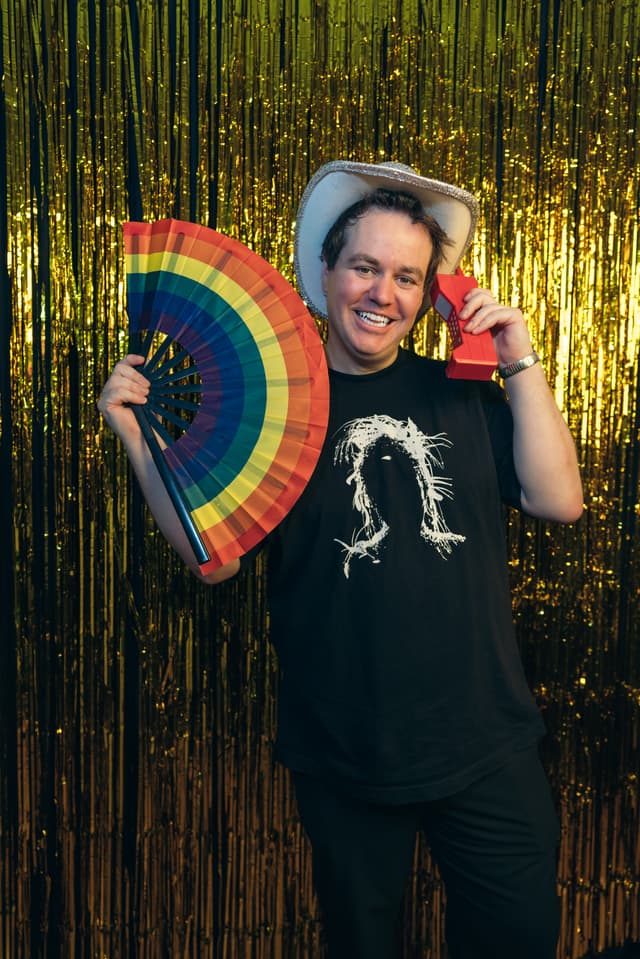NYC photo booth rental - Ben Hawes hosting a corporate event with rainbow fan props