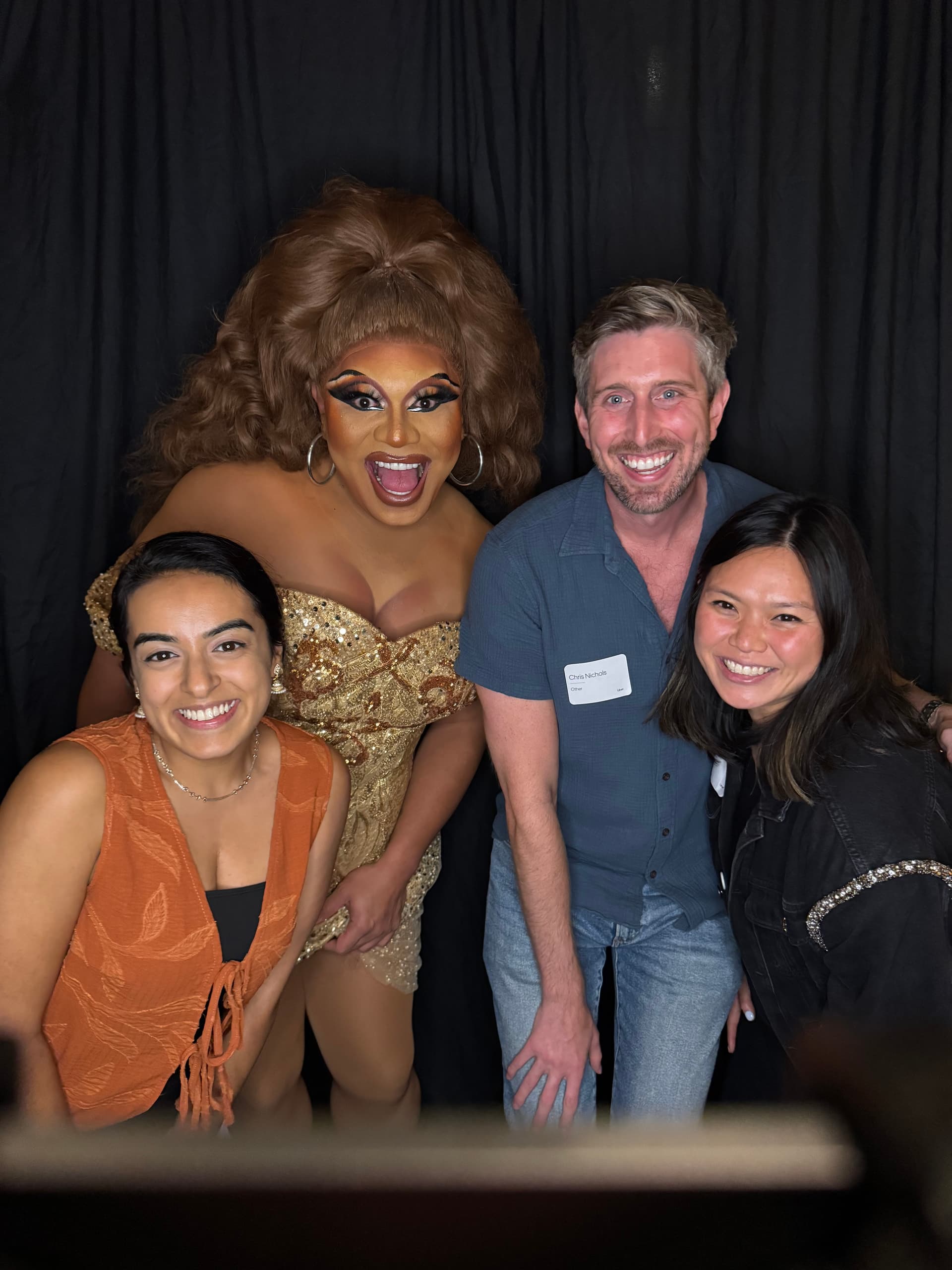 Drag queen in gold dress with guests at NYC Pride photo booth event